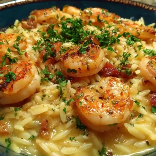 Close-up of creamy garlic shrimp orzo topped with fresh parsley, served in a dark bowl