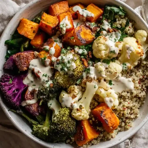 Overhead view of a colorful roasted veggie grain bowl with tahini drizzle.