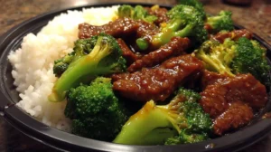Overhead view of homemade Panda Express broccoli beef served next to steamed white rice on a shallow plate