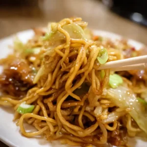 Chopsticks lifting saucy Panda Express-style chow mein noodles with cabbage and green onions