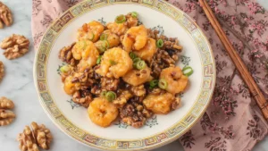 Plate of honey walnut shrimp coated in creamy honey-mayo sauce with candied walnuts.