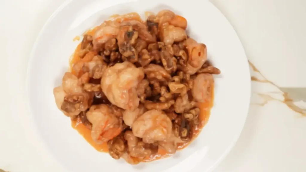 Plate of honey walnut shrimp coated in creamy honey-mayo sauce with candied walnuts
