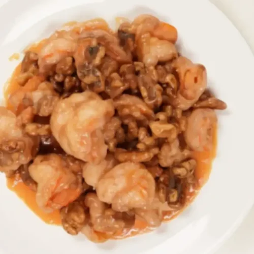 Plate of honey walnut shrimp coated in creamy honey-mayo sauce with candied walnuts