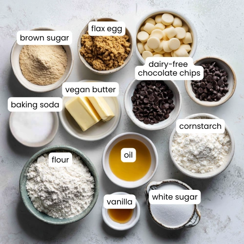 Flat lay of flour, sugars, vegan butter, coconut oil, flax egg, and chocolate chips on a kitchen counter.