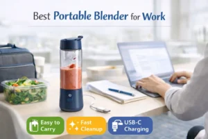 Portable blender for work on a desk next to a laptop, notebook, and morning smoothie
