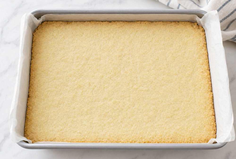 Pre-baked shortbread crust in a parchment-lined pan for easy lemon bars