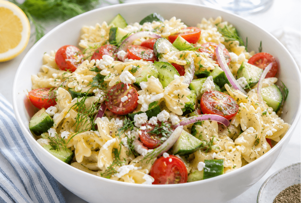 Cucumber tomato pasta salad with bow tie pasta, herbs, red onion, and feta