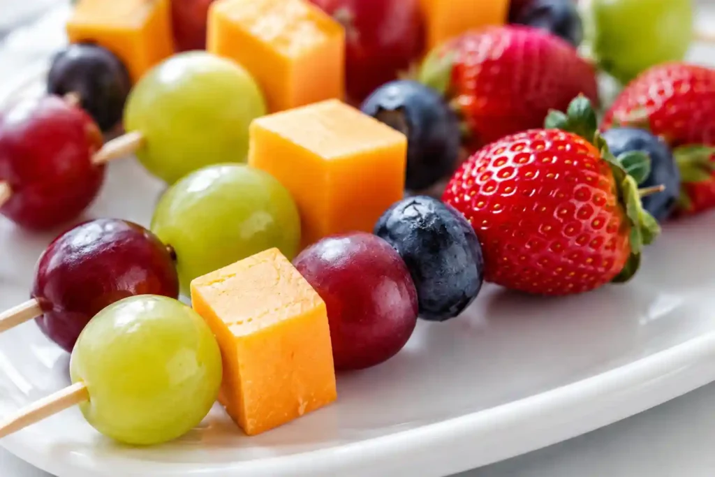 Sharp close-up of grape cheddar and berry skewers showing juicy grapes, firm cheddar cubes, and fresh berries