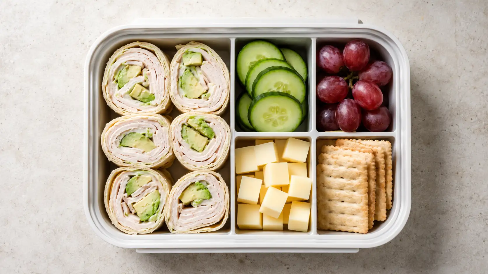 Easy bento box meal with wrap slices, cucumber, grapes, cheese, and crackers