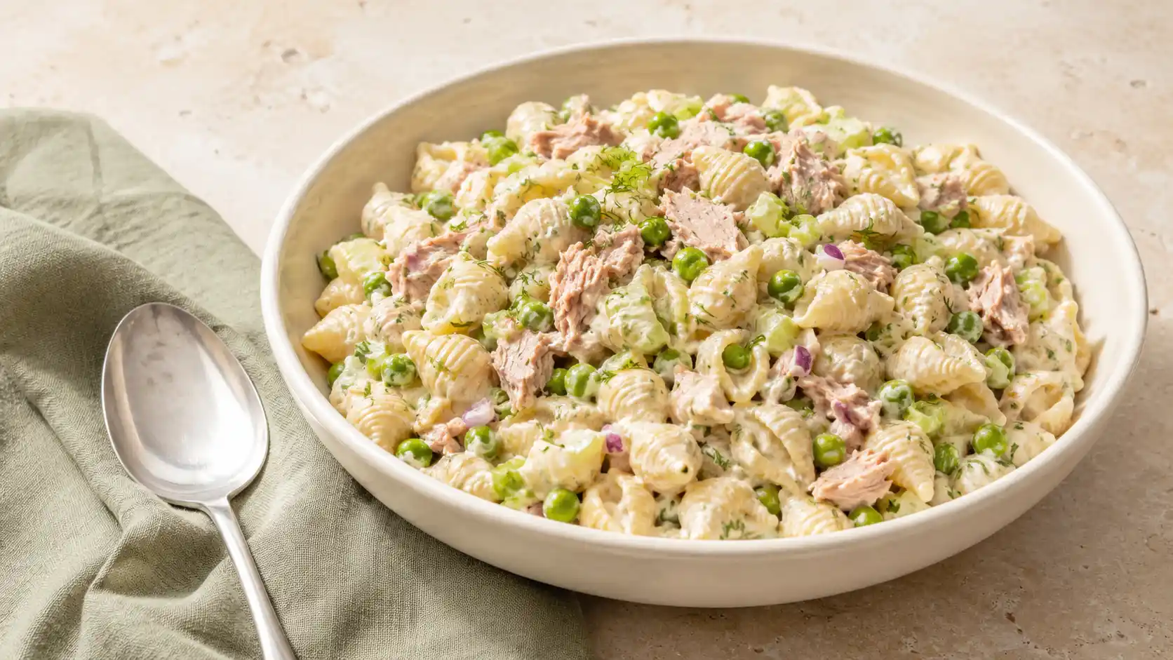 Creamy tuna pasta salad with shell pasta, tuna, peas, celery, red onion, and dill